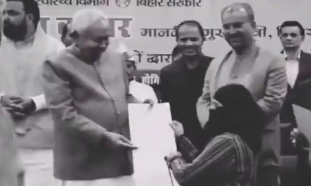 Bihar Chief Minister Nitish Kumar handing a document during a public program amid hijab controversy
