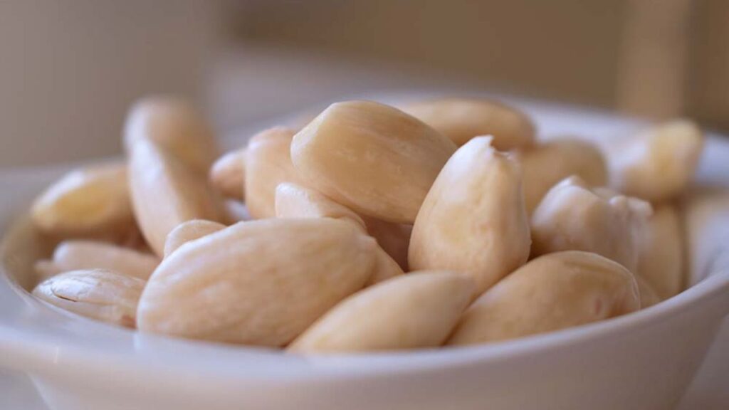 Bowl of peeled soaked almonds commonly consumed as a health food