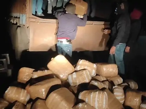 Police officials unloading seized cannabis packets from a truck during night operation in India