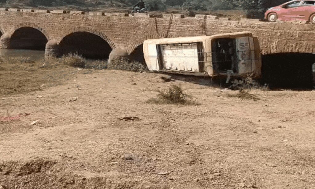 नदी किनारे पलटी हुई बस के पास राहत-बचाव में जुटी टीम, एंबुलेंस और स्थानीय लोग मौजूद