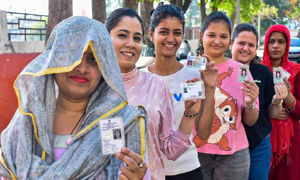 Women voters standing in queue holding voter ID cards during an election in Madhya Pradesh