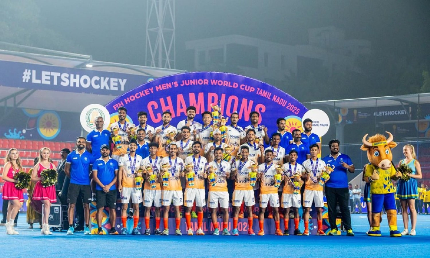 Indian players celebrate after winning the Men's Junior World Cup, with the Argentina team in the background.