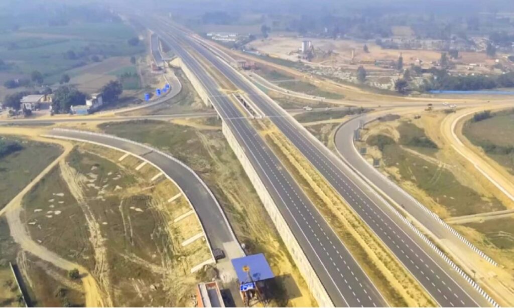 ग्रीनफील्ड एक्सप्रेसवे का निर्माण कार्य, चौड़ी सड़क और मशीनों के साथ मजदूर काम करते हुए दिखाई देते हैं