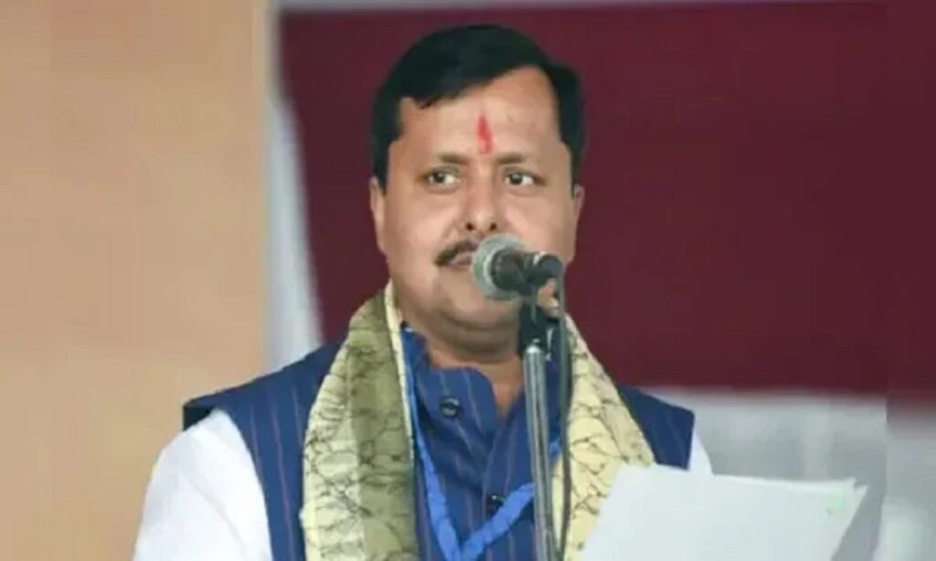 बीजेपी नेता नितिन नवीन सार्वजनिक कार्यक्रम में मंच पर बैठे हुए, पार्टी के झंडे की पृष्ठभूमि में