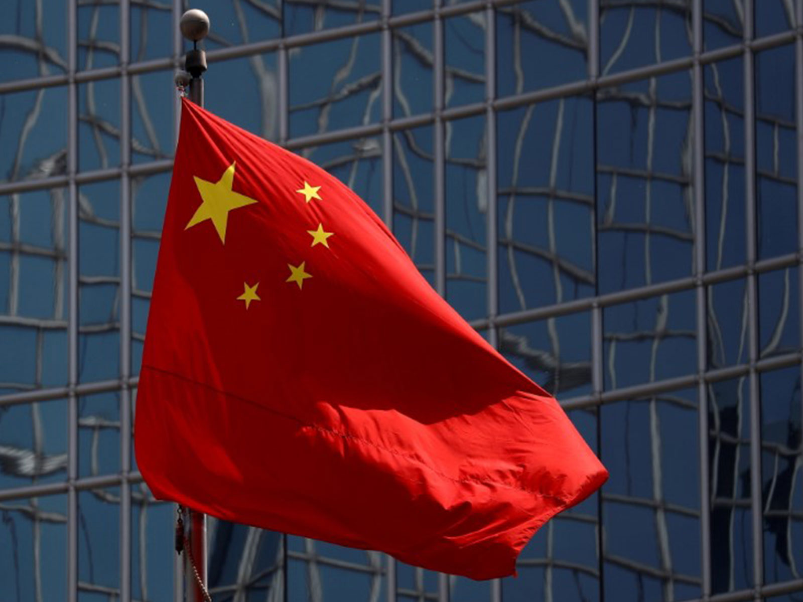 Chinese national flag outside a modern building, used as representative visual for China-related controversy