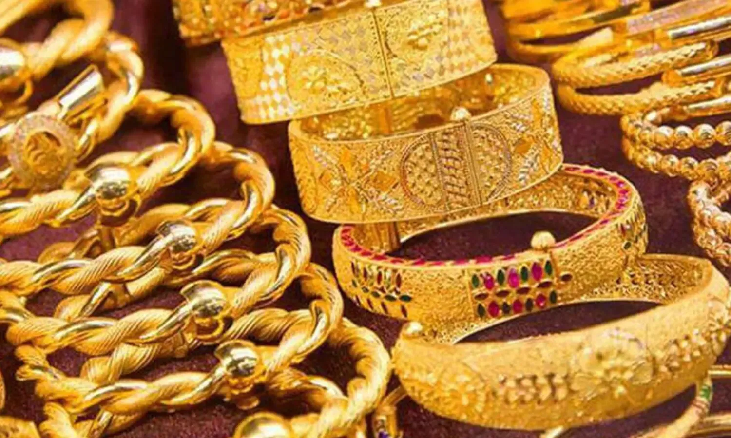 Close up of various heavy gold bangles and jewelry displayed for sale in a jewelry store