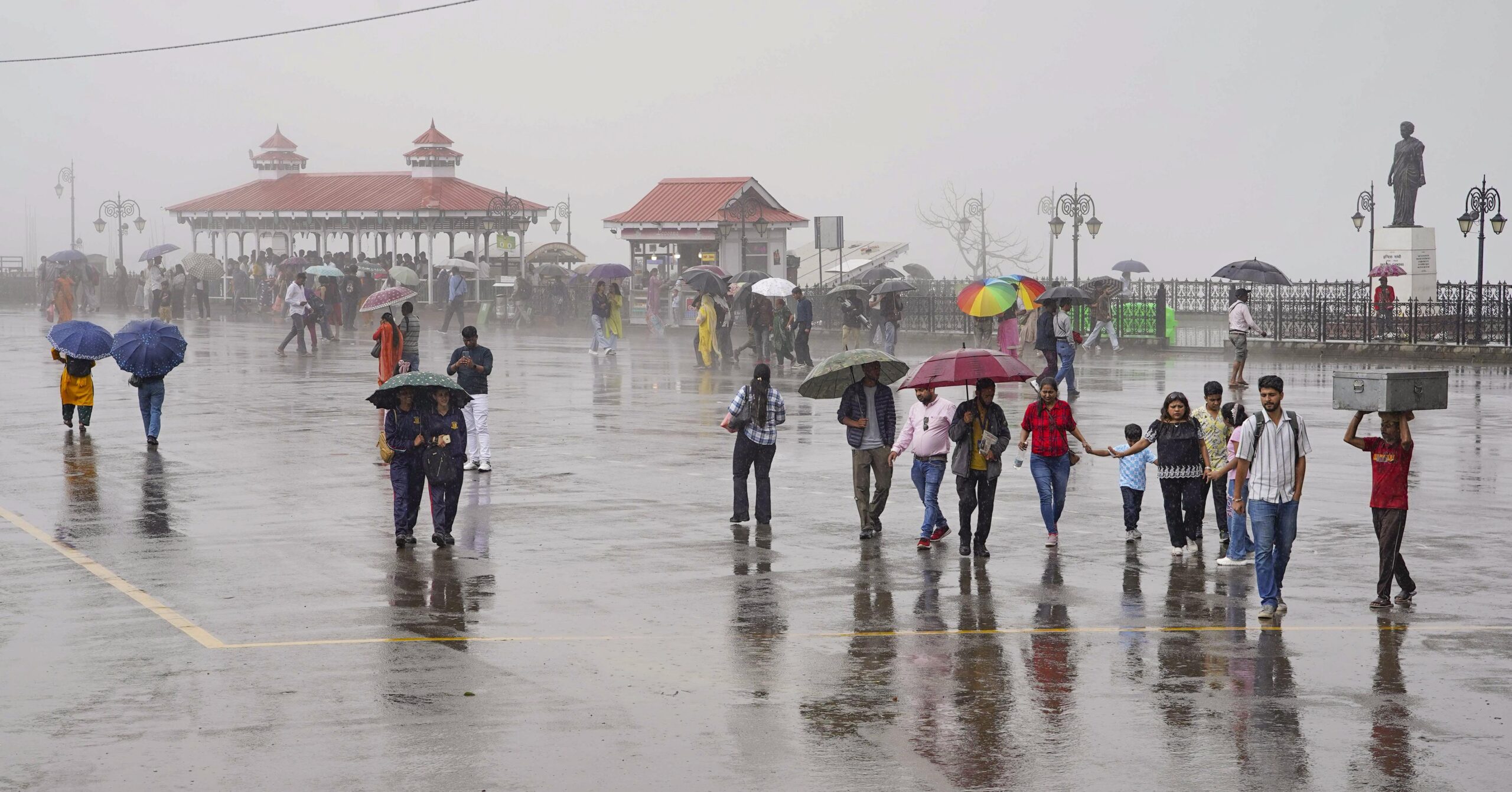 People with umbrellas walking in heavy rain in Delhi.