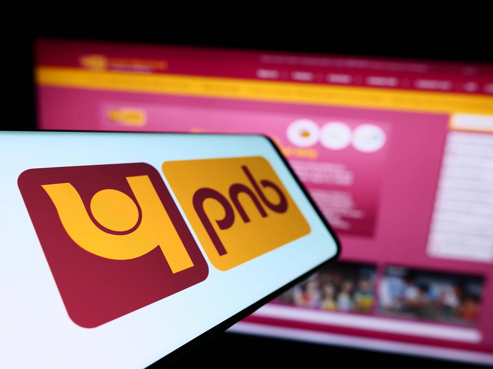 PNB logo displayed on a smartphone screen against the backdrop of the official website for financial results news