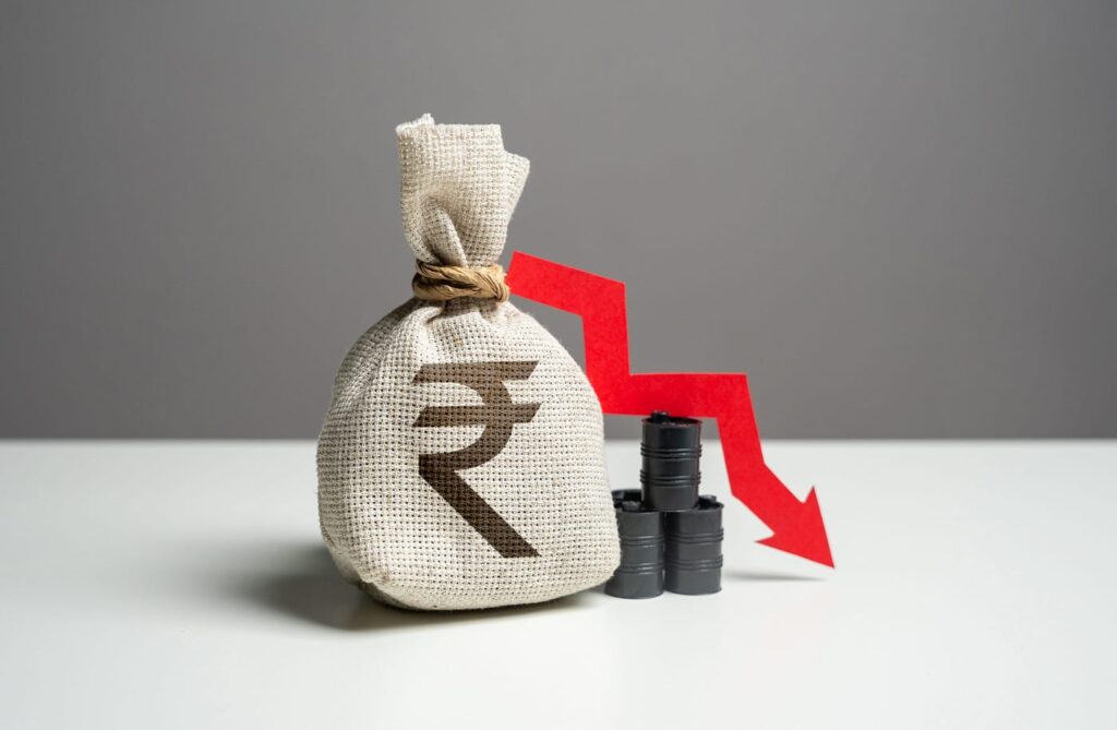 Illustration showing Indian Rupee symbol falling against a backdrop of US dollar bills and declining charts.