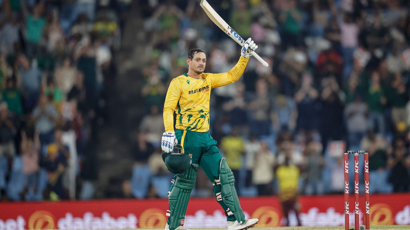Quinton de Kock raises his bat after scoring a match-winning century against West Indies.