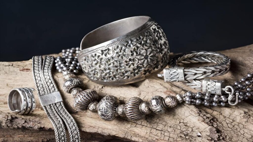 Antique silver jewelry and decorative ornaments displayed on a rustic wooden surface.
