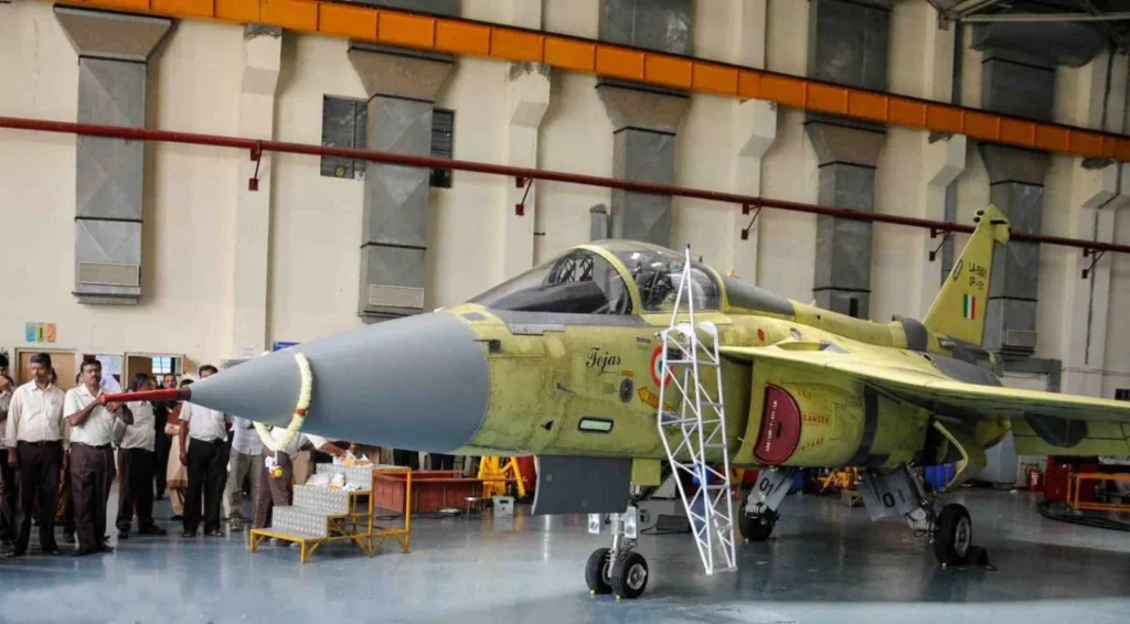 An Indian Air Force LCA Tejas fighter jet stationary on the tarmac during a technical inspection.