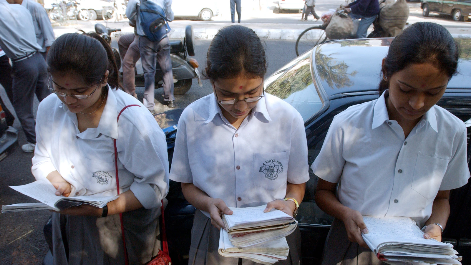 Students discussing the CBSE Class 12 Physics question paper outside an examination center in India.