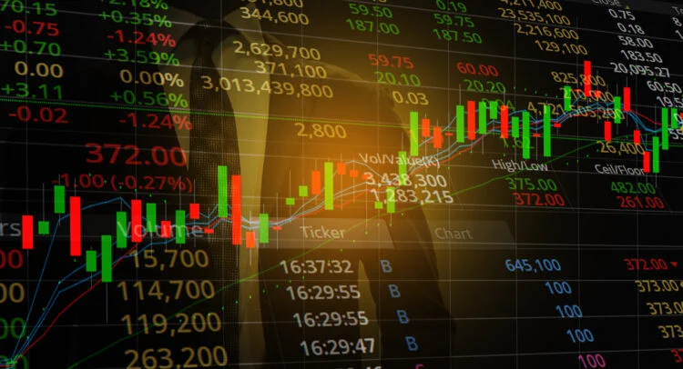 Gold bars stacked over a glowing financial candlestick chart showing market growth trends.