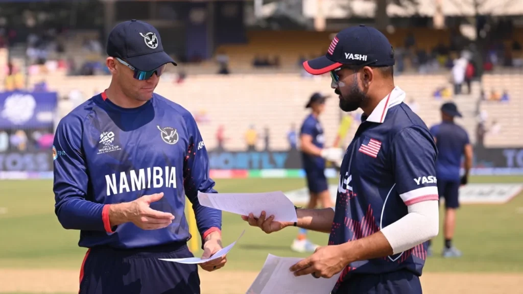 USA and Namibia cricket captains discussing team sheets during the T20 World Cup toss.
