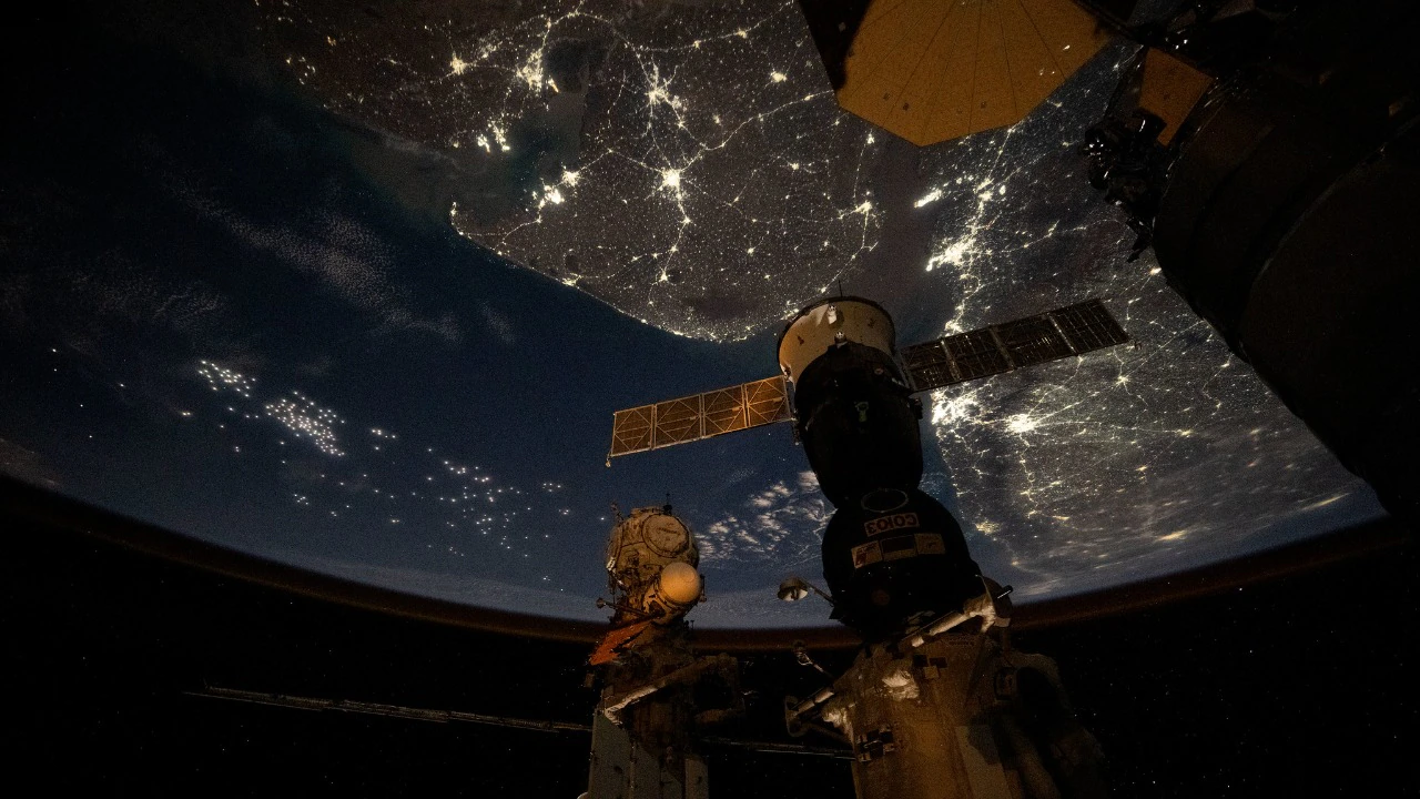 Nighttime view of India glowing from space, capturing bright city lights and the dark Himalayan border from the ISS.