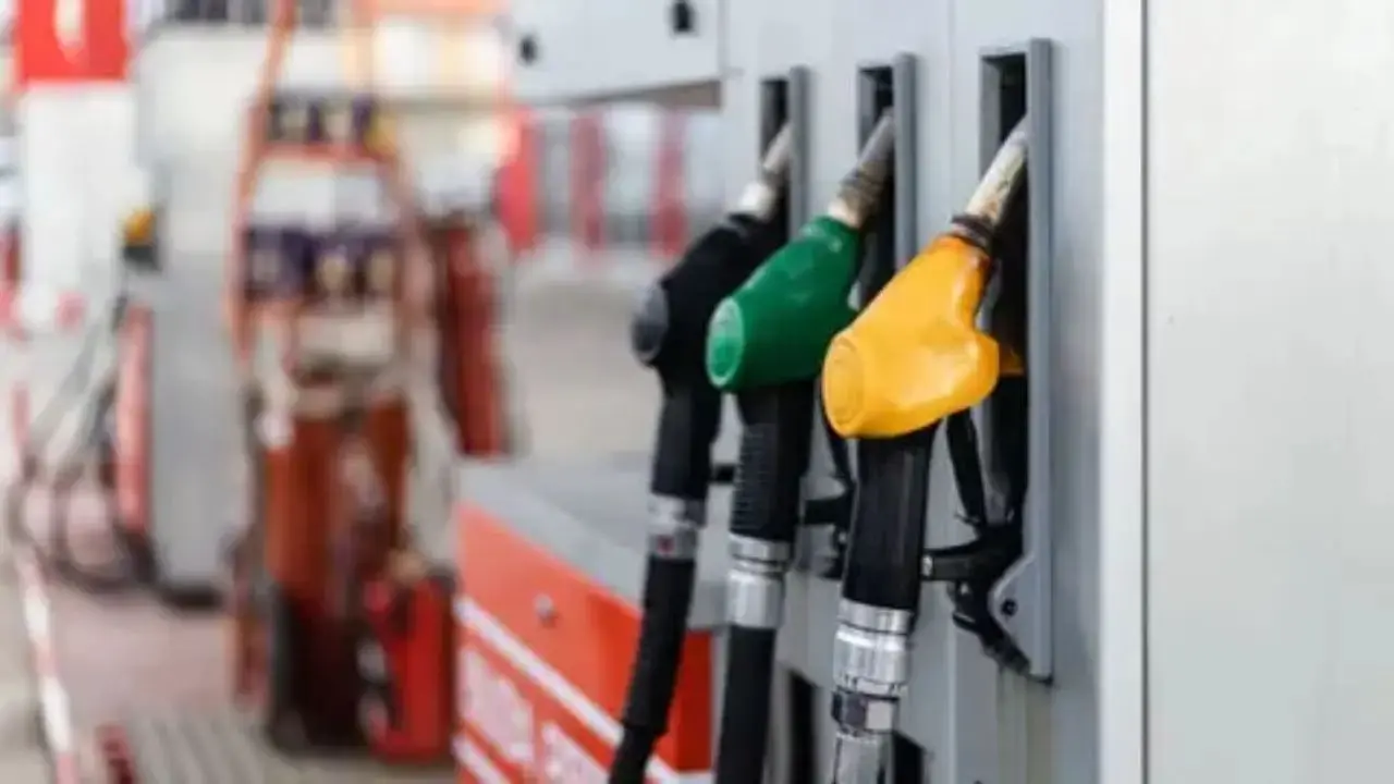 A fuel nozzle dispensing petrol at a filling station in Jaipur with digital price board in background showing price hike.