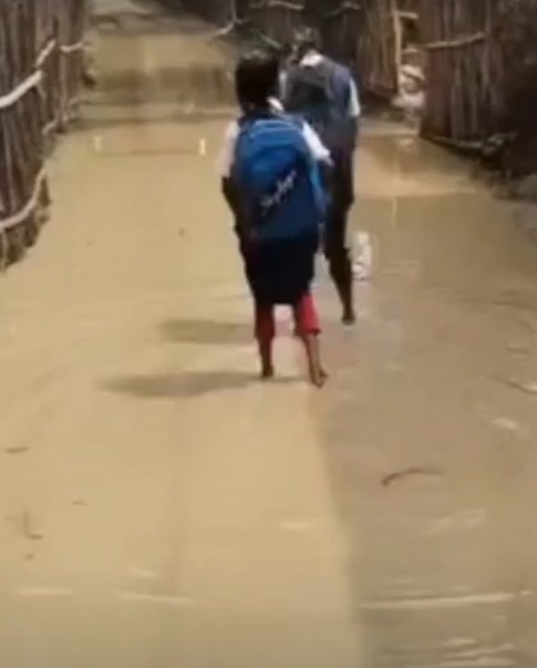 Tribal children in Sidhi forced to walk through knee-deep water on a submerged path to get to school.